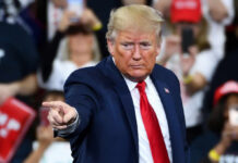 Epic Fury Unleashed: Trump Targets Iran A man in a blue suit and red tie gestures while speaking at a rally