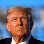 Close-up portrait of a serious-looking political figure outdoors