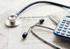Stethoscope and calculator on health insurance documents