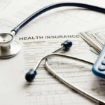 Stethoscope and calculator on health insurance documents
