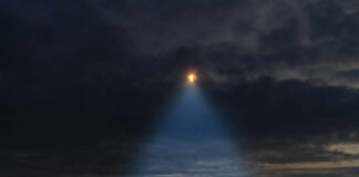 A mysterious figure standing on a mountain under a dark sky with a beam of light from a UFO