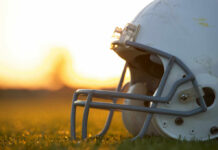 Close-up of a football helmet on a grassy field during sunset
