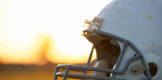 Close-up of a football helmet on a grassy field during sunset