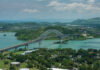 Aerial view of a bridge spanning over turquoise water surrounded by greenery