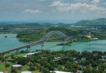 Aerial view of a bridge spanning over turquoise water surrounded by greenery