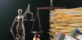 A bronze statue of Lady Justice holding scales, with legal documents and a gavel in the background
