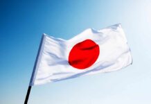 Japanese flag with a red circle on a white background waving against a blue sky