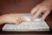 Bible Quotes CRIMINALIZED — Canada’s Shocking Faith Crackdown A childs hand and an adults hand pointing at text in a book