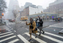 People crossing a snowy street in an urban area during a winter storm