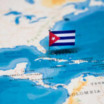 A small Cuban flag placed on a map highlighting Cuba in the Caribbean