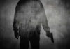 Silhouette of a person holding a gun against a textured background