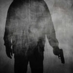 Silhouette of a person holding a gun against a textured background