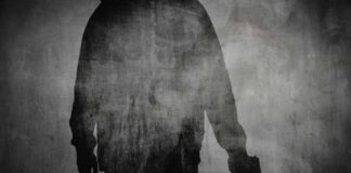 Silhouette of a person holding a gun against a textured background