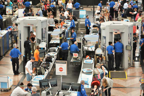 Busy airport security checkpoint with travelers and TSA agents