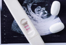 Pregnancy test next to an ultrasound image and two white tablets