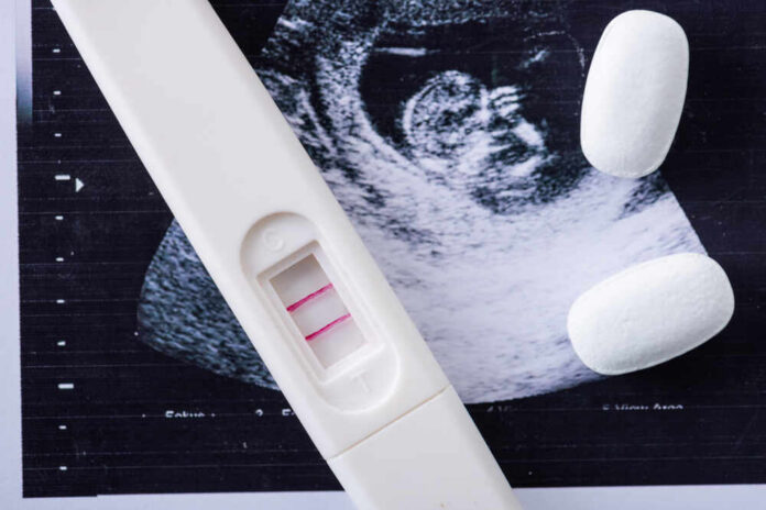 Pregnancy test next to an ultrasound image and two white tablets