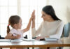 A mother and daughter sharing a high-five while studying together