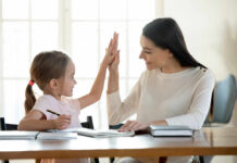 A mother and daughter sharing a high-five while studying together