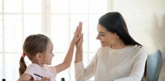 A mother and daughter sharing a high-five while studying together