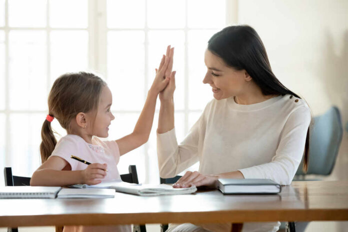 A mother and daughter sharing a high-five while studying together