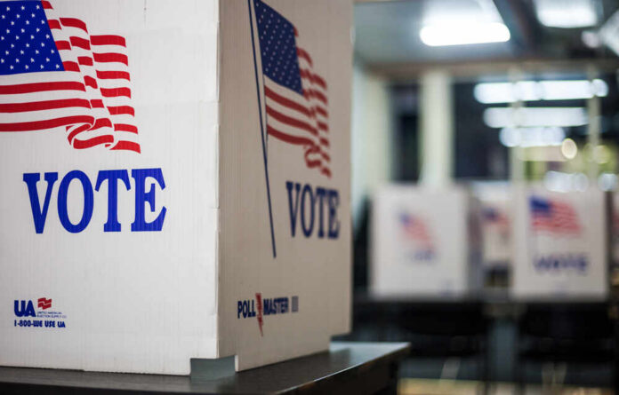 shutterstock_1837302940.jpg Voting booths with American flags in a polling station