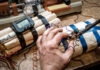 A hand working on a device resembling an explosive with wires and a timer