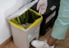 Person in gloves disposing of waste in an infectious waste bin