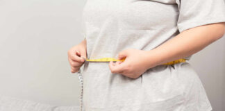 Person measuring their waist with a tape measure