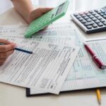 Person calculating financial figures with documents and a calculator