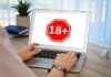 Person using a laptop displaying an age restriction sign