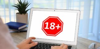 Person using a laptop displaying an age restriction sign