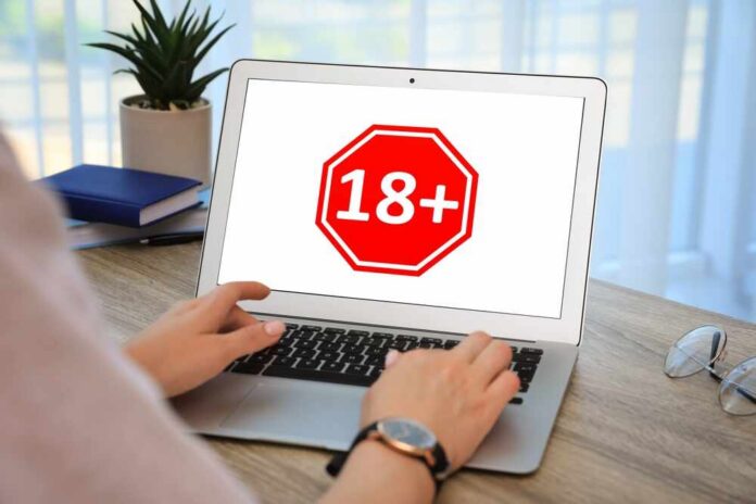 Person using a laptop displaying an age restriction sign