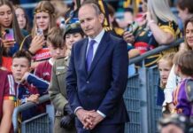 A man in a suit stands among a crowd at a public event