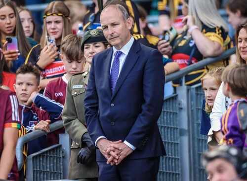 A man in a suit stands among a crowd at a public event