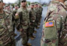 Uniformed soldiers in formation with an American flag patch visible