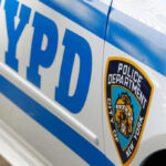 Close-up of a New York Police Department vehicle showcasing the badge and blue stripes