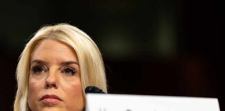 Close-up of a female speaker at a government hearing with a serious expression