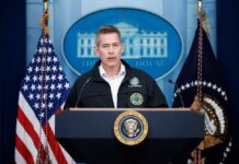 Government official speaking at a podium in front of the White House backdrop