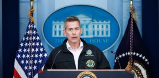 Government official speaking at a podium in front of the White House backdrop