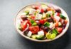 A vibrant salad with tomatoes, cucumbers, olives, and feta cheese