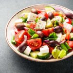A vibrant salad with tomatoes, cucumbers, olives, and feta cheese