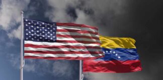 Flags of the United States and Venezuela waving against a cloudy sky