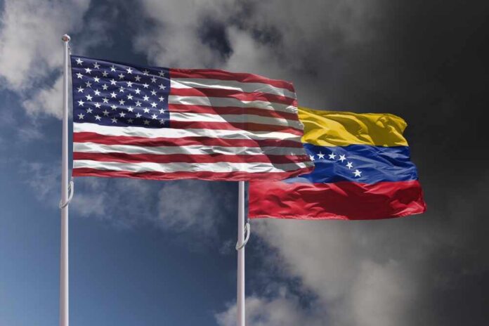 Flags of the United States and Venezuela waving against a cloudy sky