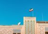 Building with intricate patterns and the Iranian flag against a clear blue sky