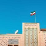 Building with intricate patterns and the Iranian flag against a clear blue sky