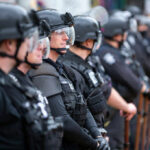 Line of riot police in tactical gear standing ready for crowd control