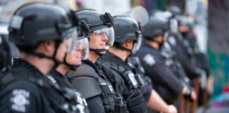 Line of riot police in tactical gear standing ready for crowd control