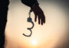 Silhouette of a hand holding handcuffs against a sunset