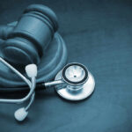 A wooden gavel next to a stethoscope on a dark surface