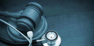 A wooden gavel next to a stethoscope on a dark surface